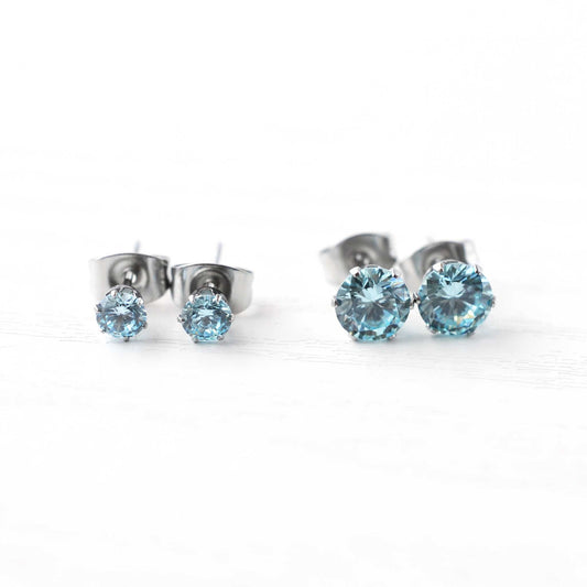 Pair of silver stud earrings with blue gemstones on a white background