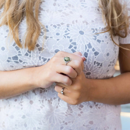 Close-up of two hands holding each other with a white lace garment in the background