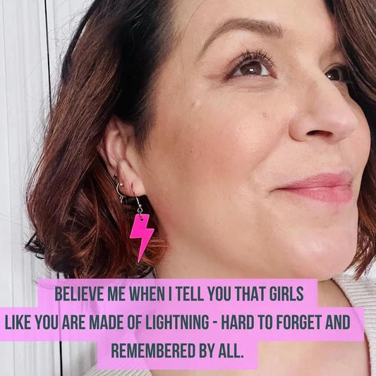 Close-up of a woman's face with a pink lightning bolt earring and a motivational quote.