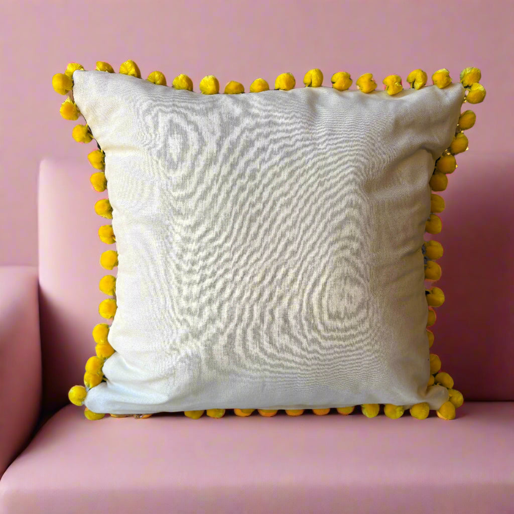 Rear view of the Deepest Jungle cushion showing the plain cream back with acid yellow pompoms, on a pink sofa
