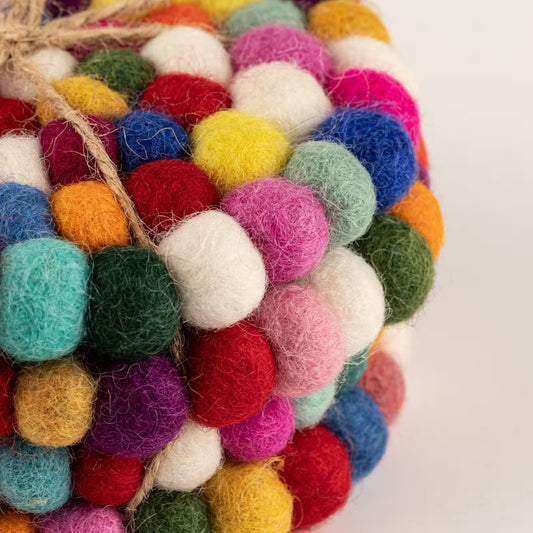 Close-up of stacked multicolour felt ball round coasters tied with jute twine, showing pink, blue, red, yellow and green wool balls