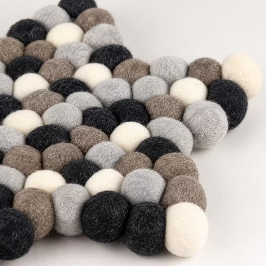 Close-up of one point of the grey felt ball star mat, showing charcoal, grey, taupe and cream wool balls