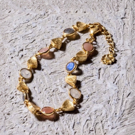 Gold bracelet with colorful stones on a textured gray surface