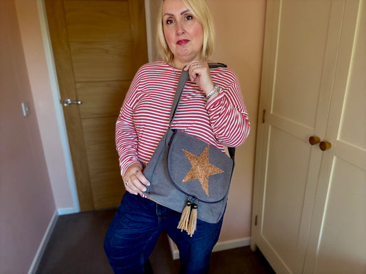 Woman holding a gray bag with a star design in a room.