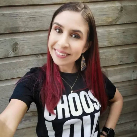 Woman with red hair wearing a black t-shirt with white text against a wooden background