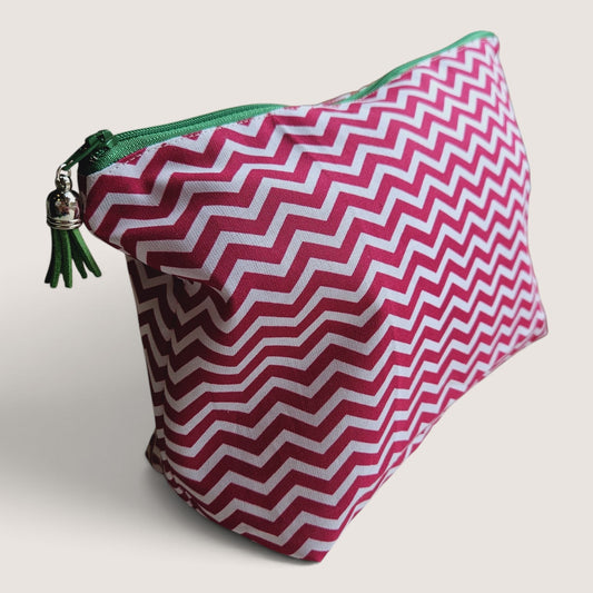 Raspberry Chevron wash bag angled to show the pink and white chevron print, green zip and green suede tassel with a silver cap