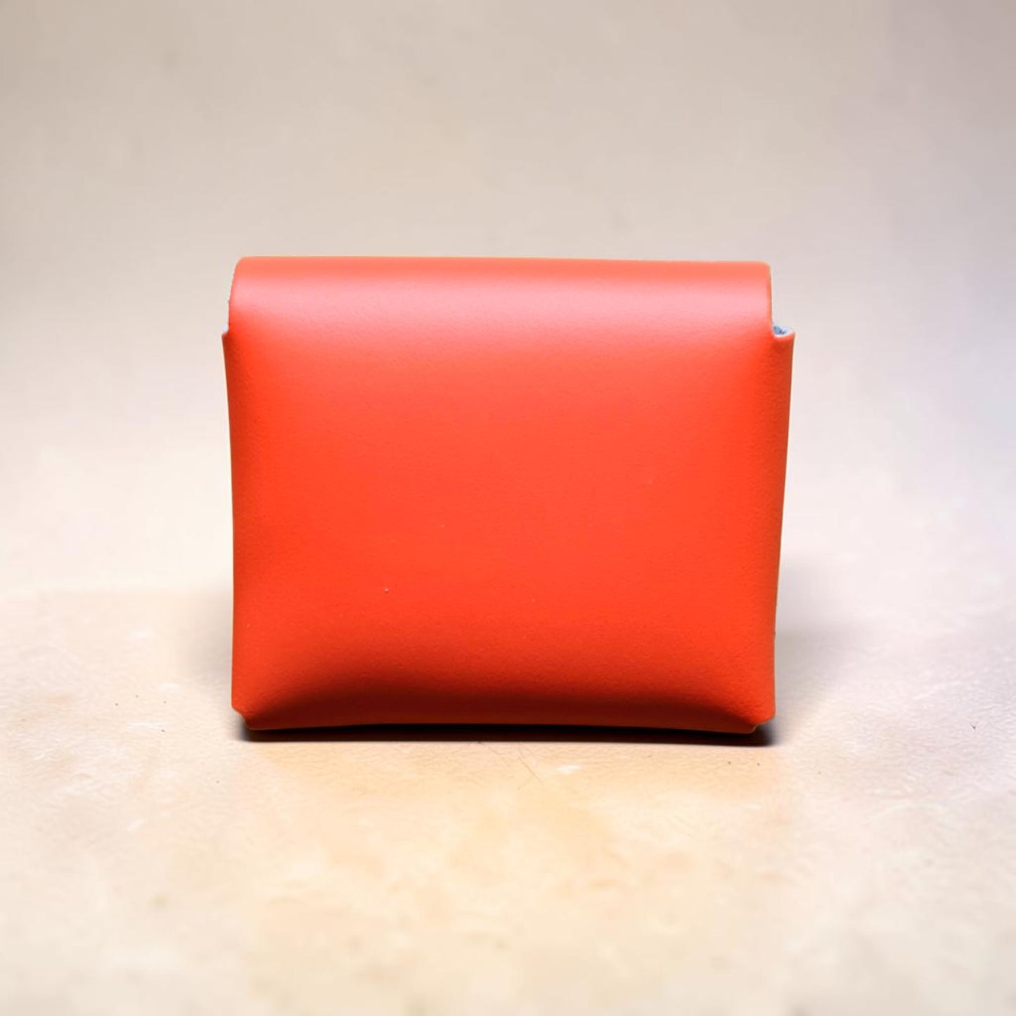 Red leather wallet on a light wooden surface