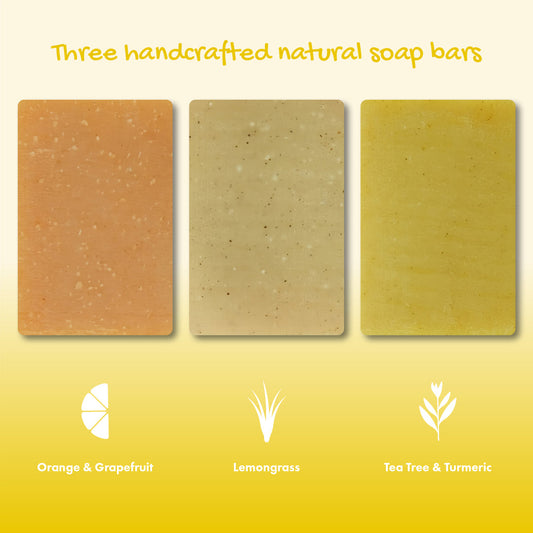 Three handcrafted natural soap bars with labels for Orange & Grapefruit, Lemongrass, and Tea Tree & Turmeric on a yellow background.