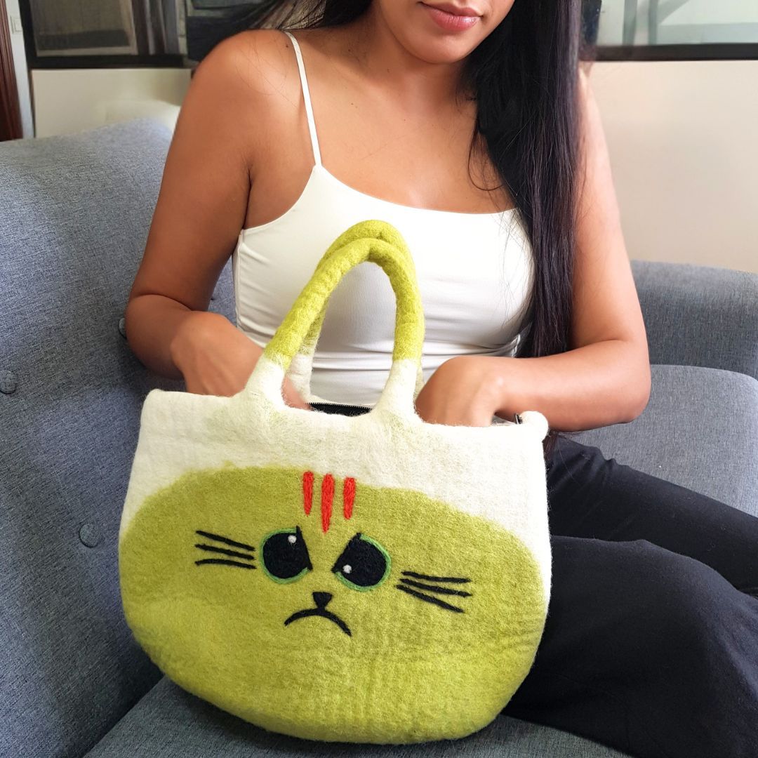 Woman sitting on a blue sofa with the Large Grumpy Cat Felted Bag on her lap