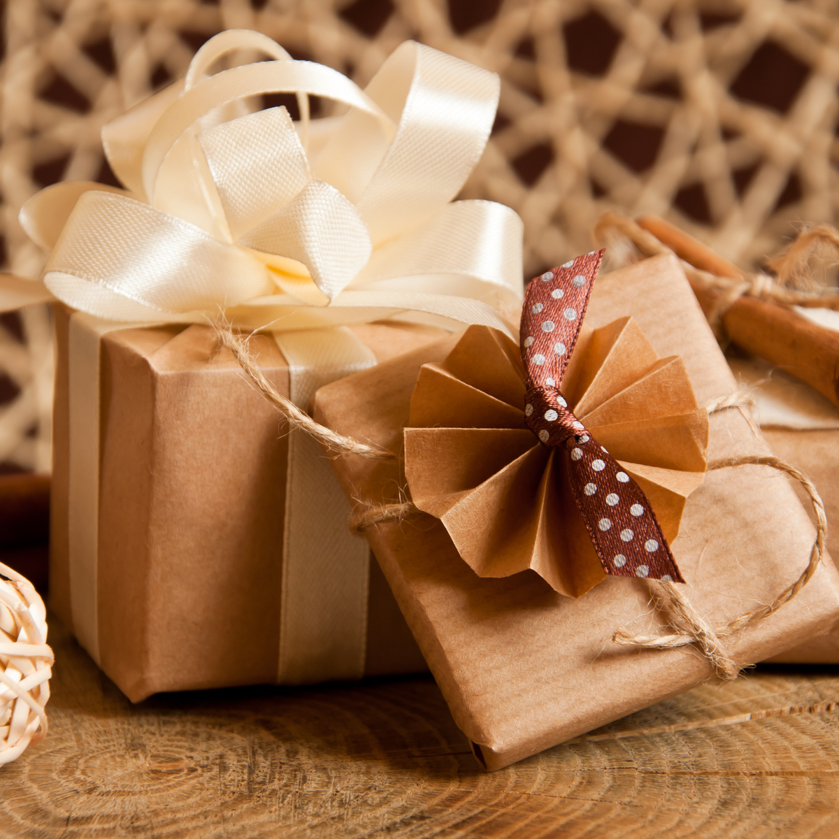 Gifts under £100: kraft-wrapped presents tied with twine, a cream satin bow and a brown polka-dot ribbon