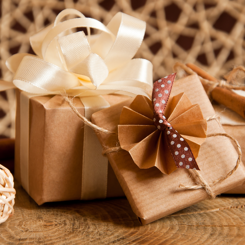 Gifts under £100: kraft-wrapped presents tied with twine, a cream satin bow and a brown polka-dot ribbon