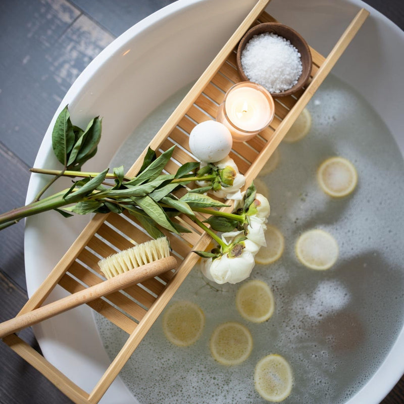 Natural bath ritual with candle, flowers, lemon slices and bath salts — Apricot Moon all‑natural Wellness Gifts.