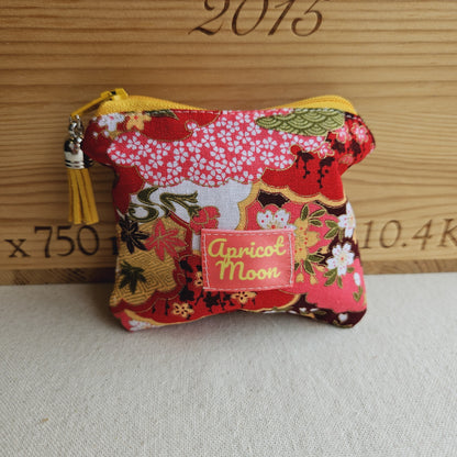Small fabric pouch with floral design and 'Apricot Moon' label on a textured surface.