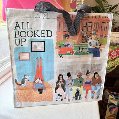 Bag with illustrations and text 'All Booked Up' on a table.