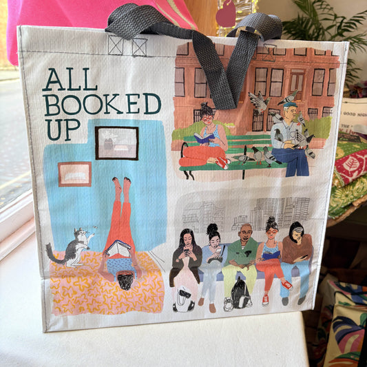 Bag with illustrations and text 'All Booked Up' on a table.