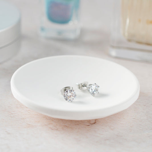 Silver earrings on a white ceramic dish with a blurred background