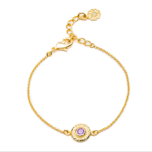 Gold bracelet with a purple gemstone on a white background