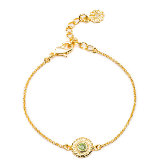 Gold bracelet with a green gemstone on a white background
