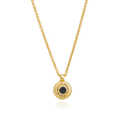 Gold necklace with a black pendant on a white background