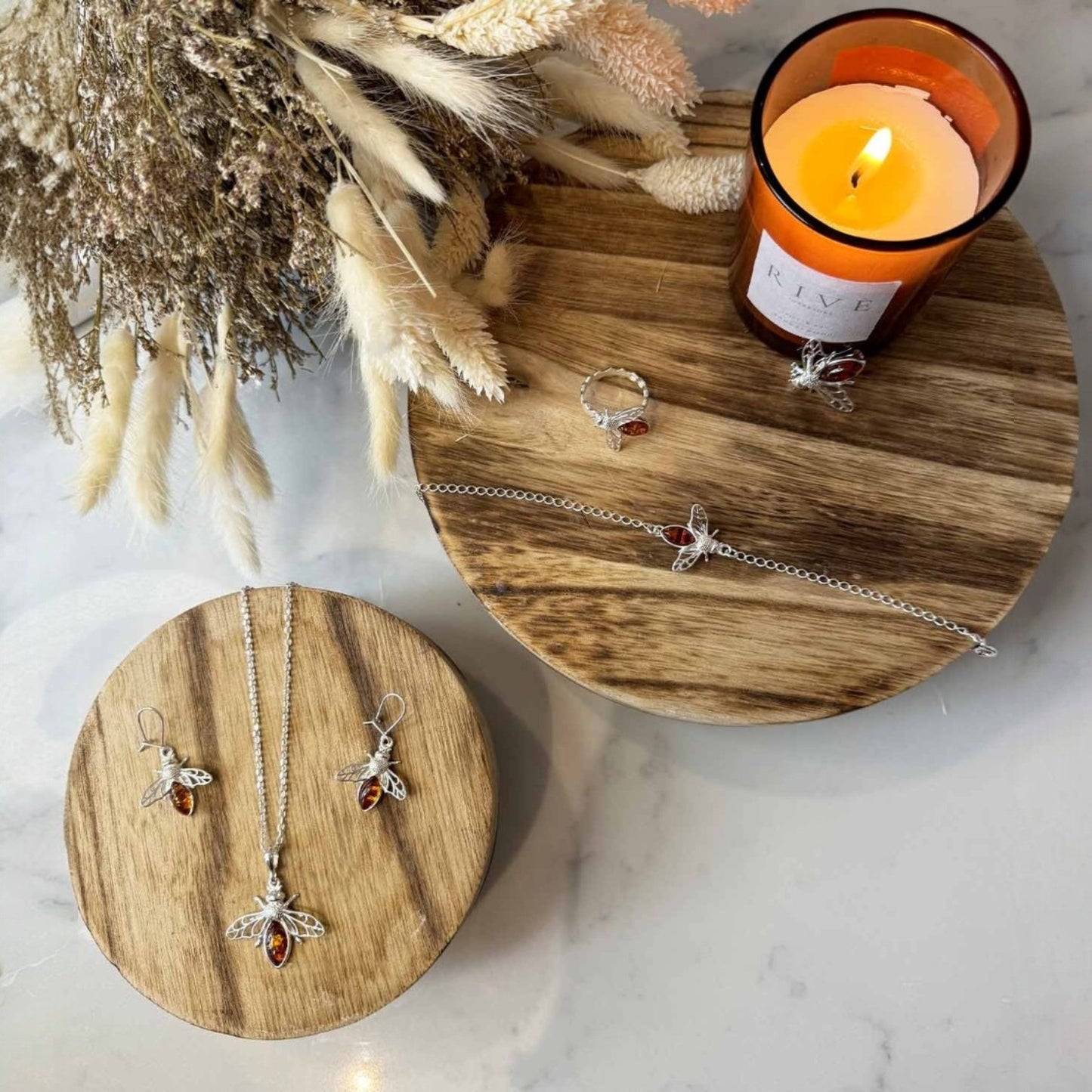 Jewelry displayed on wooden trays with a candle in the background