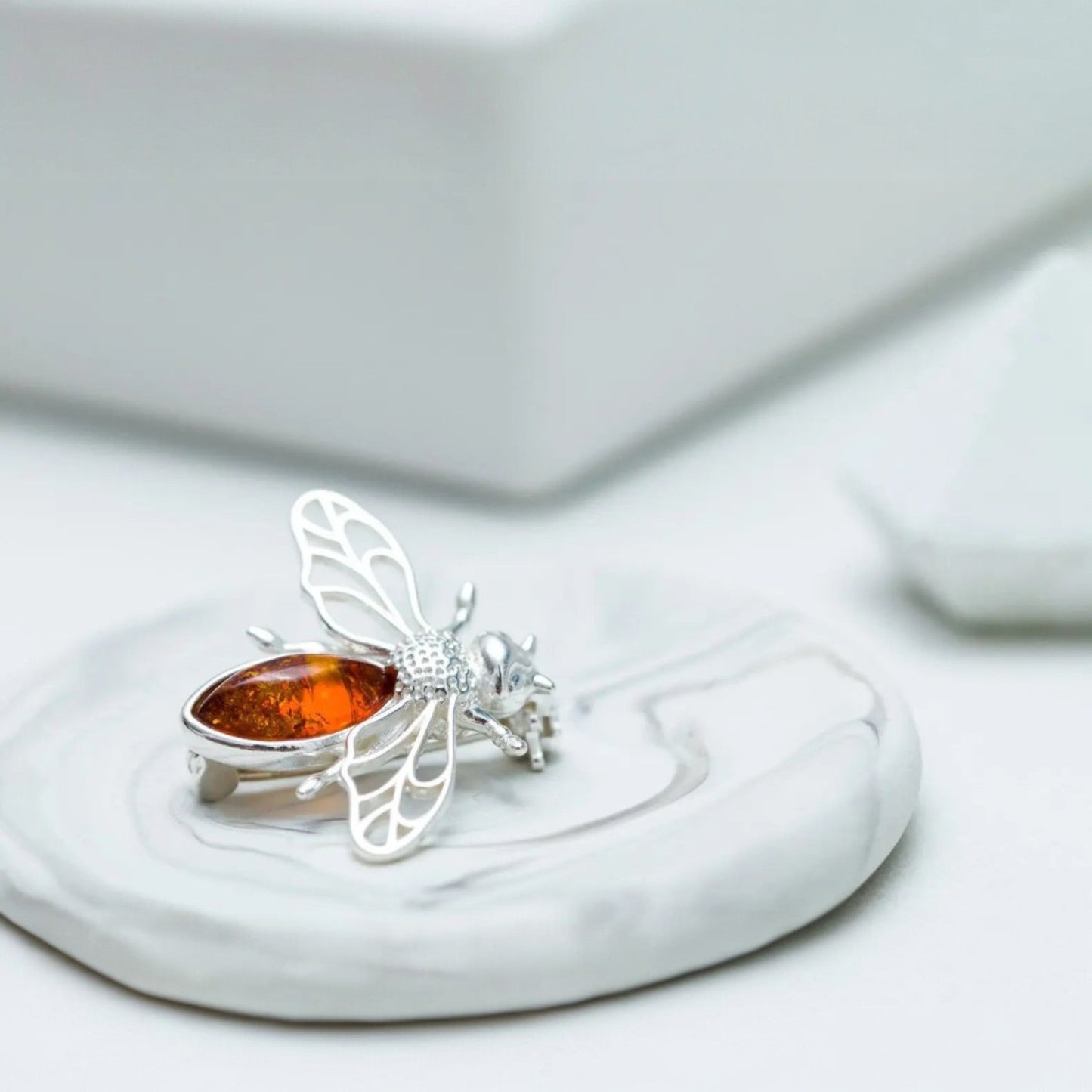 Silver ring with a butterfly design and amber stone on a white surface
