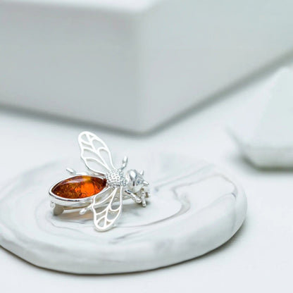Silver ring with a butterfly design and amber stone on a white surface