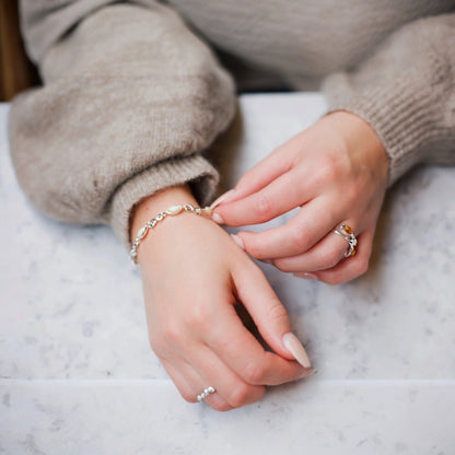 Close-up of hands wearing multiple rings on a marble surface