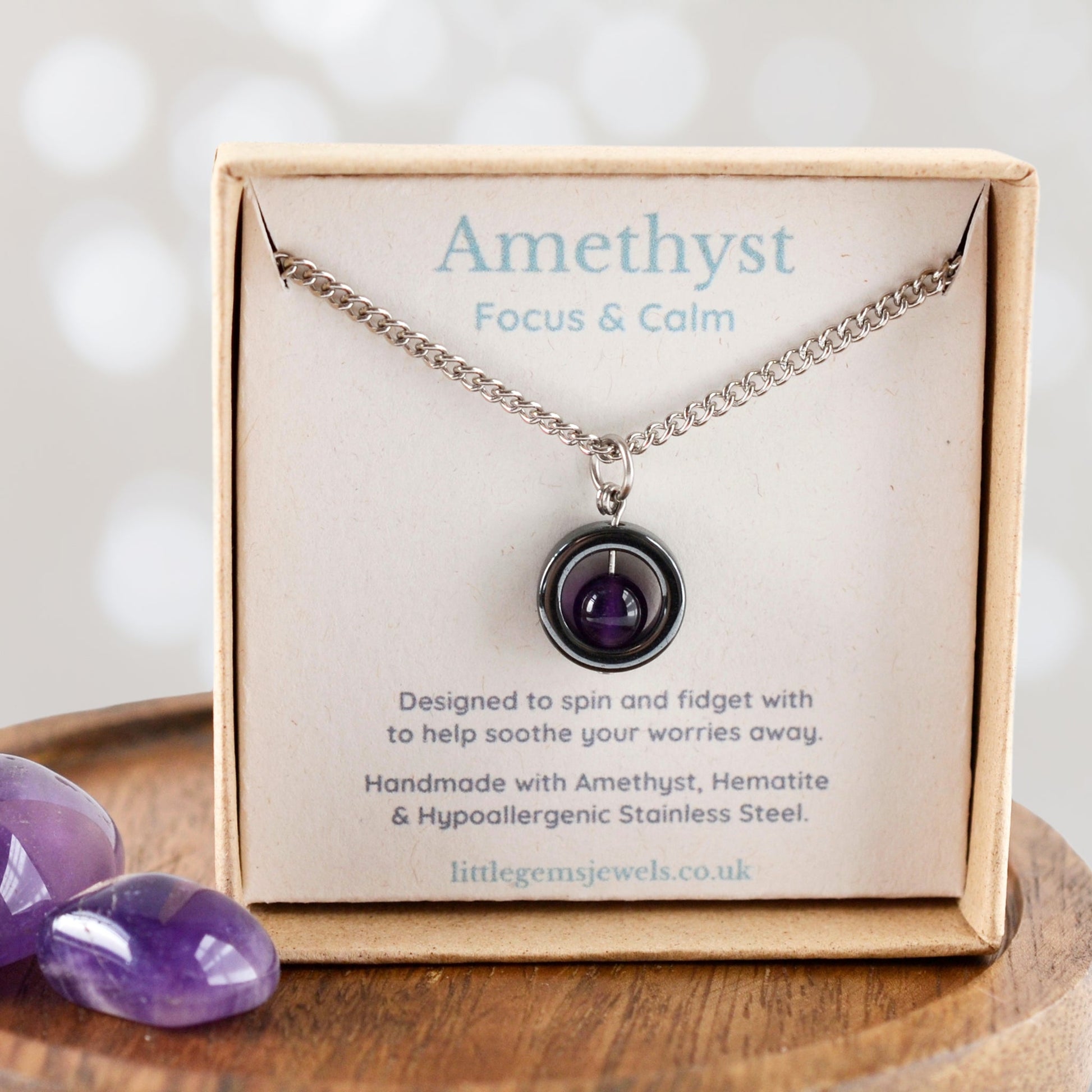 Amethyst focus and calm necklace in a box with purple stones on a wooden surface