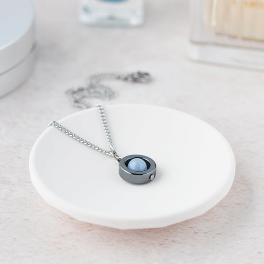 Necklace with a round pendant on a white dish