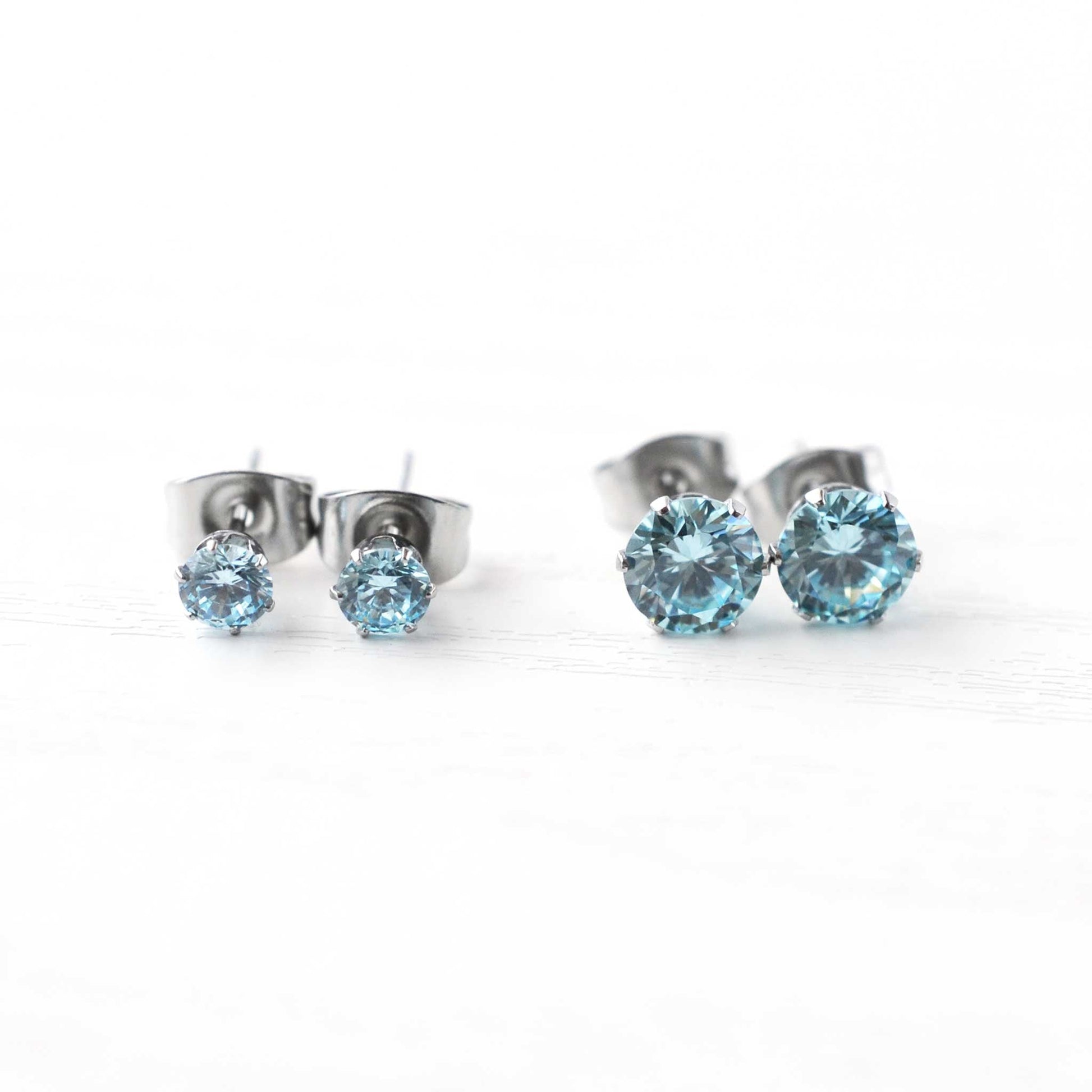 Pair of silver stud earrings with blue gemstones on a white background