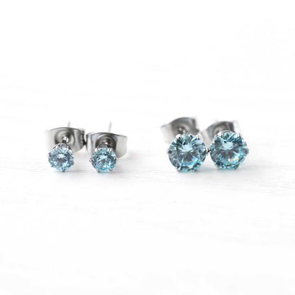 Pair of silver stud earrings with blue gemstones on a white background