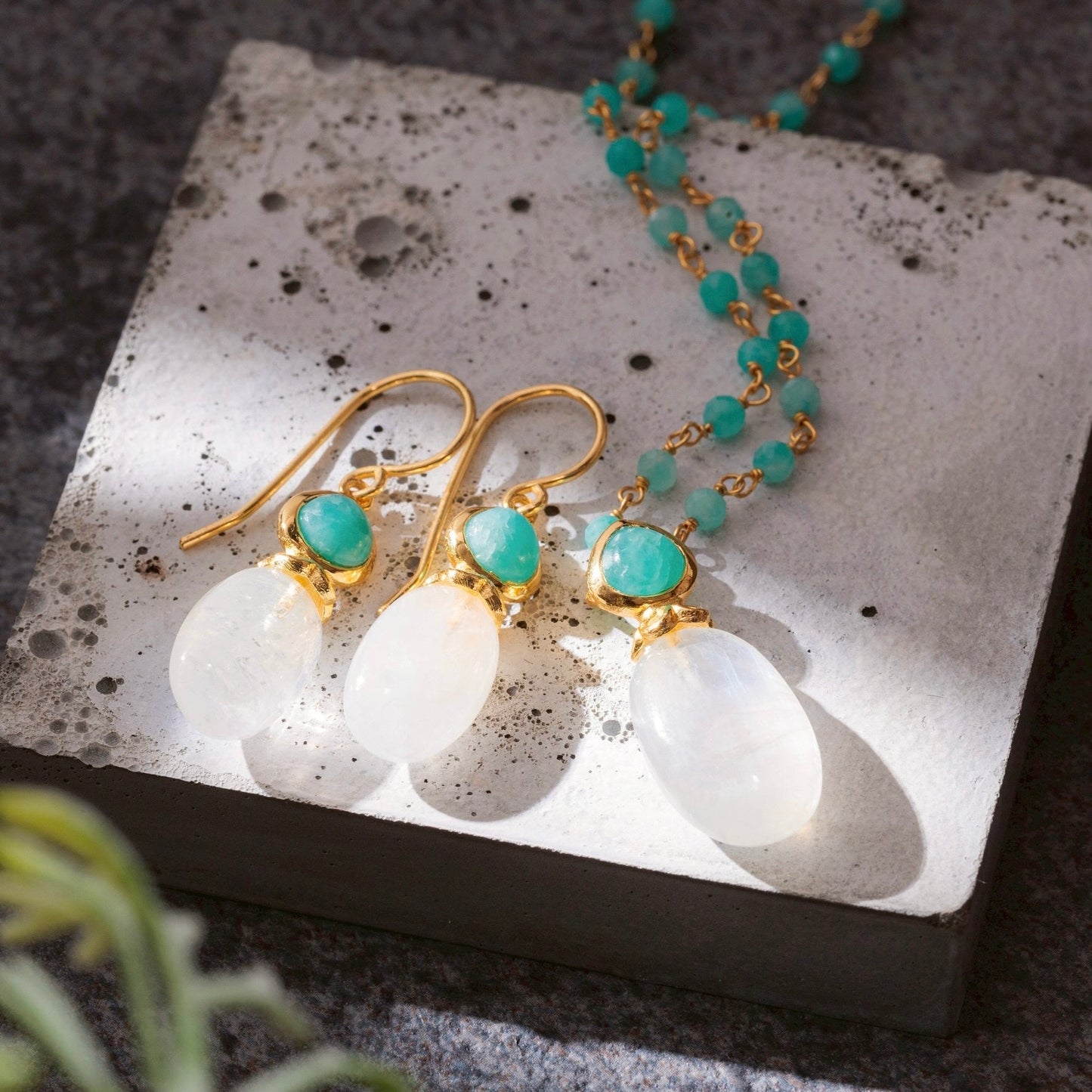 Gold earrings with turquoise stones on a white stone surface
