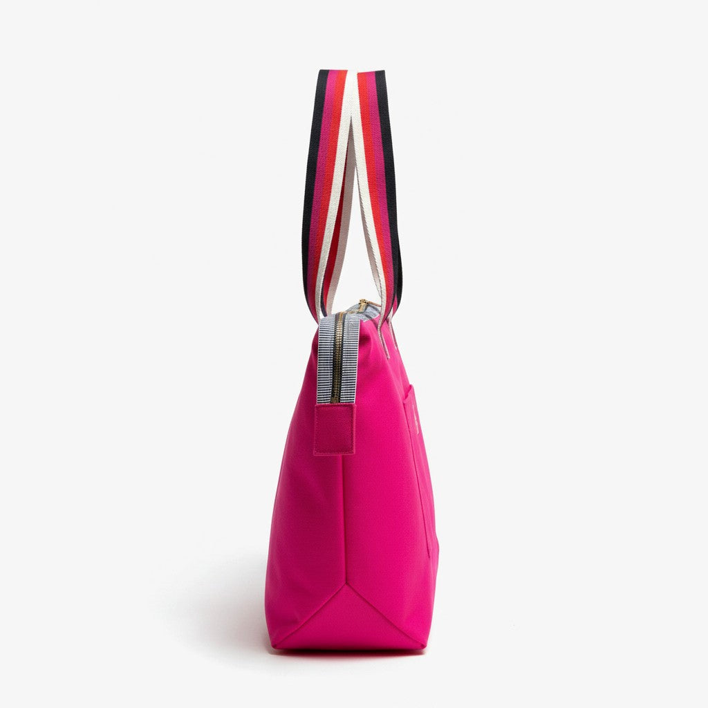 Side view of the Berry Riot bright pink shoulder tote showing the striped handles, striped zip tape and pink zip pull tab, studio shot