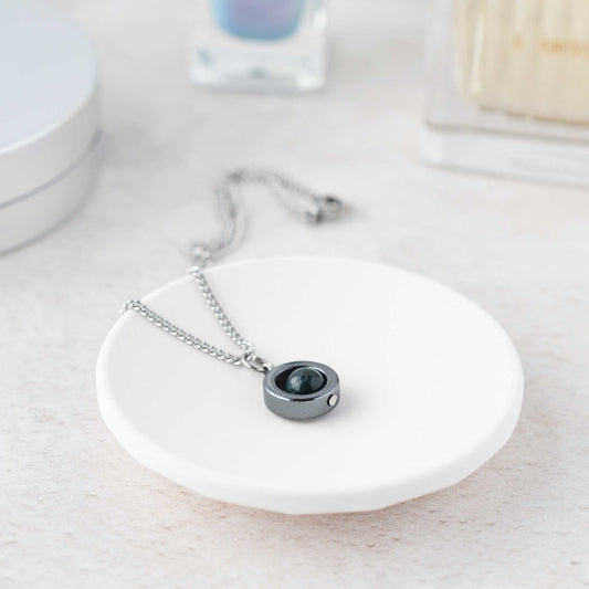 Silver necklace with a black pendant on a white surface