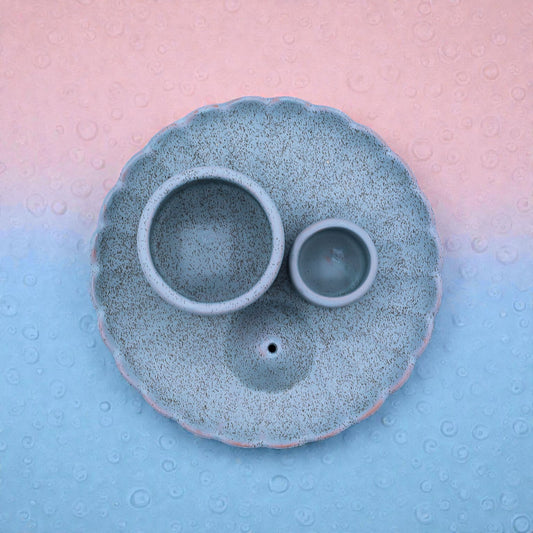 Blue ceramic incense burner with two bowls on a textured pink and blue background