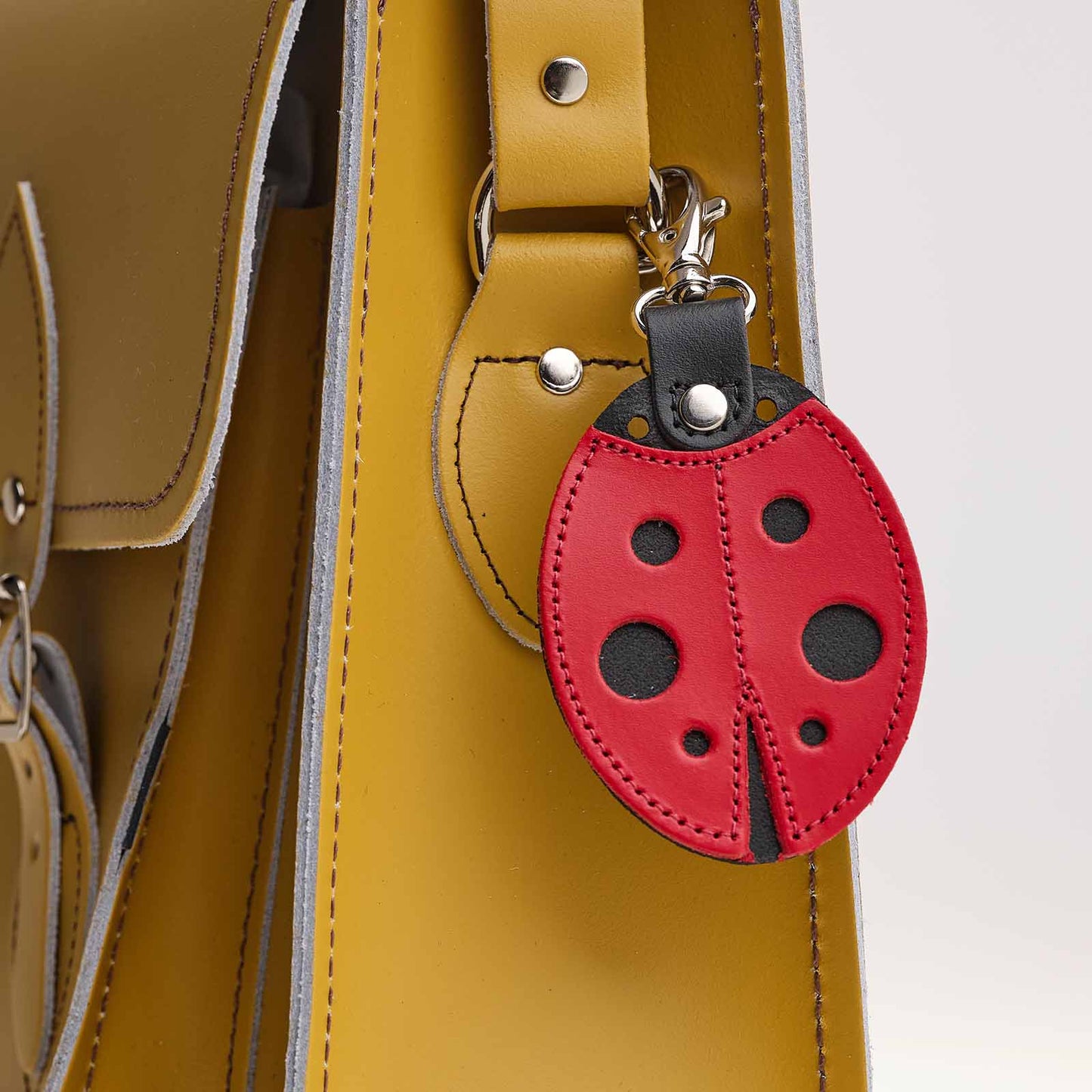 Red ladybug-shaped keychain attached to a yellow bag.