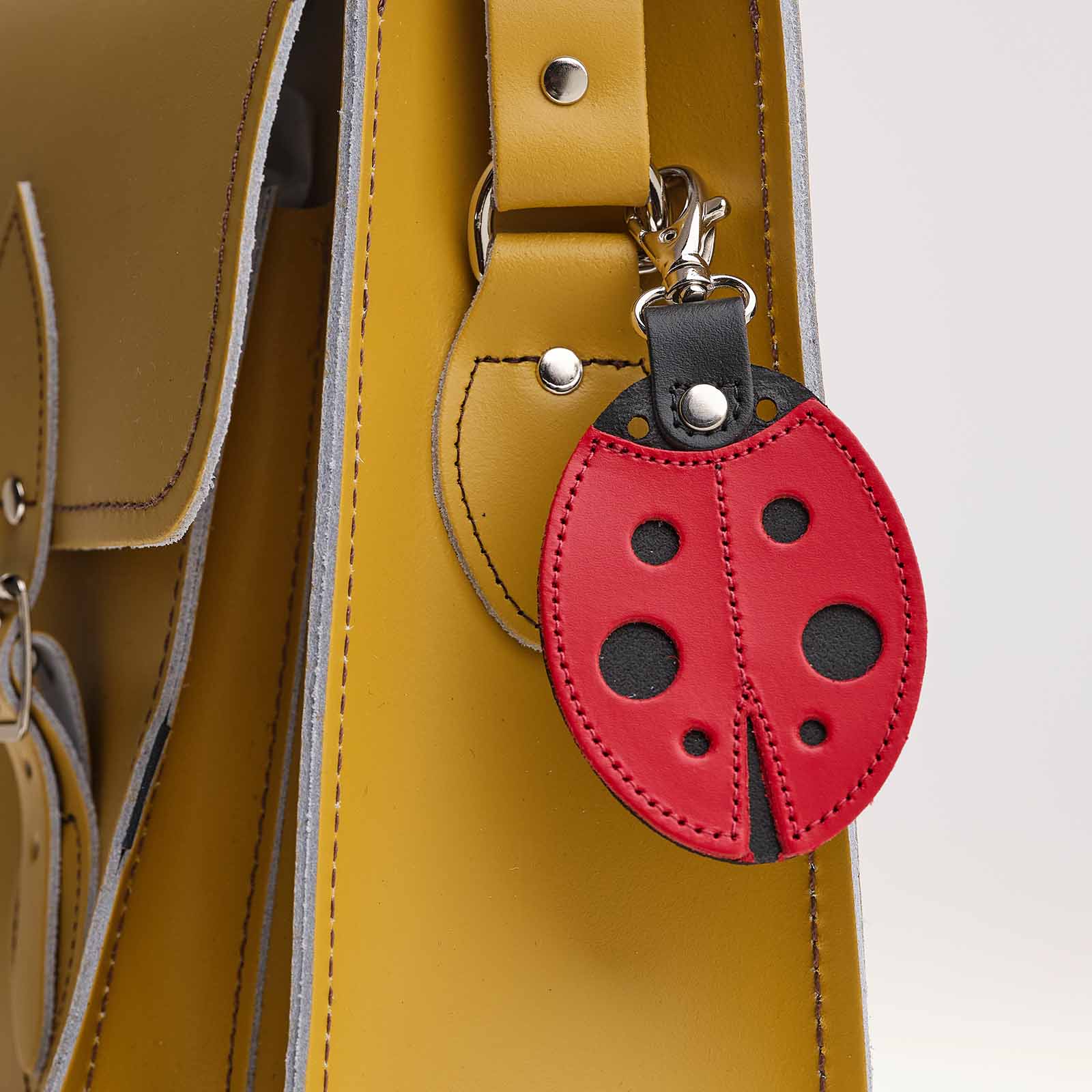 Red ladybug-shaped keychain attached to a yellow bag.