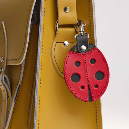 Red ladybug-shaped keychain attached to a yellow bag.