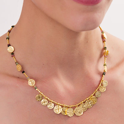 Gold necklace with circular pendants on a person against a neutral background