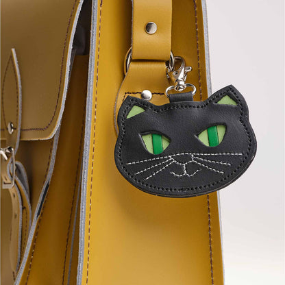 Black cat-shaped keychain attached to a yellow bag.