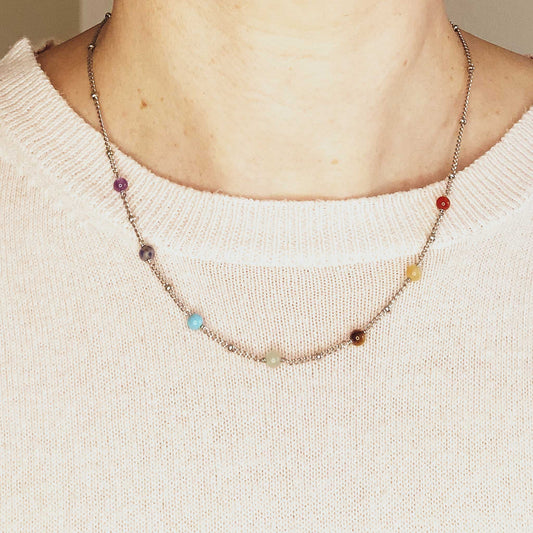 Necklace with multicolored beads worn by a person against a neutral background