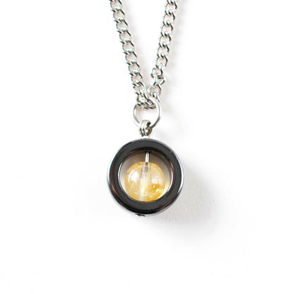 Necklace with a round pendant featuring a yellow gemstone on a white background