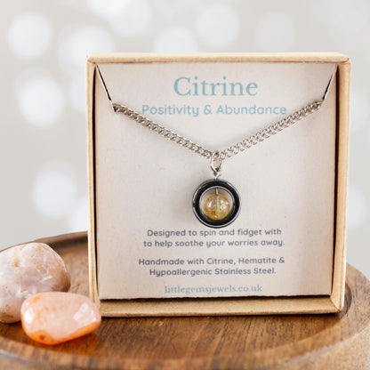 Citrine necklace in a box with card detailing properties and materials, on a wooden surface.