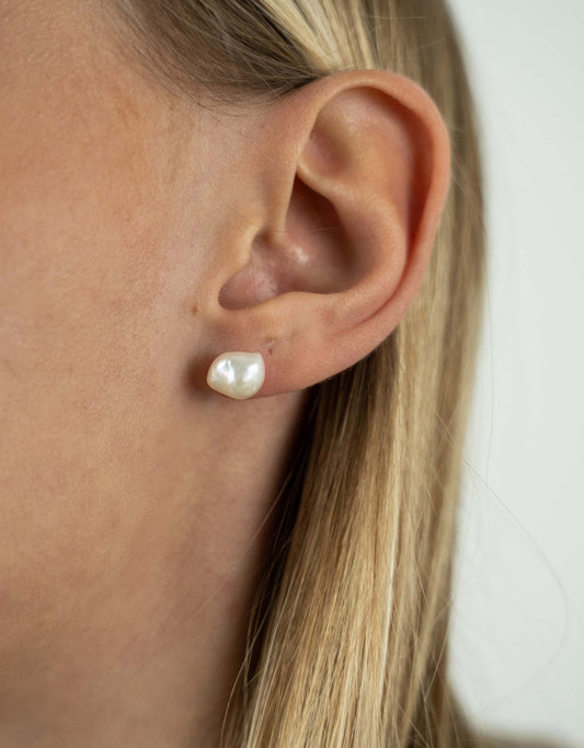 Close-up of an ear wearing a pearl earring with a blurred background