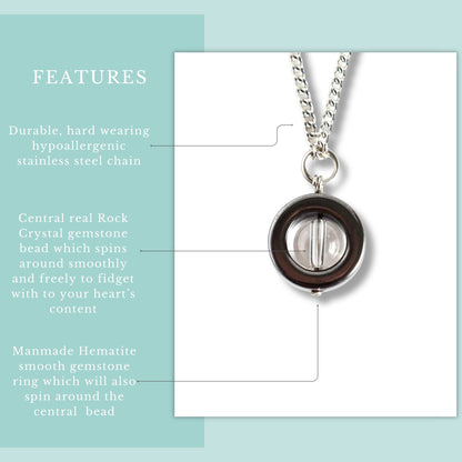 Necklace with central rock crystal gemstone bead and manmade hematite smooth gemstone ring on a light blue background.