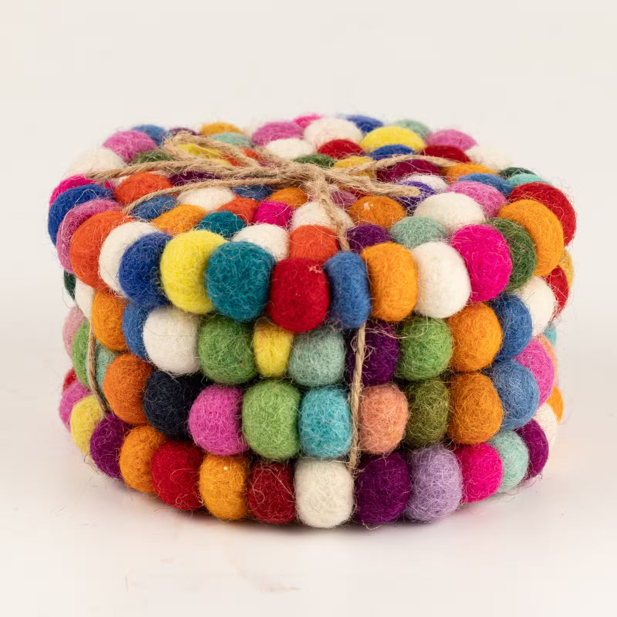 Side view of four multicolour felt ball round coasters stacked and tied with jute twine