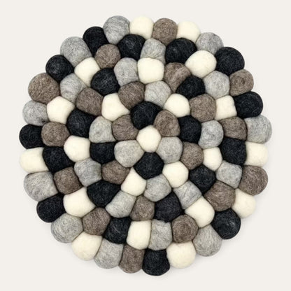 Grey felt ball round placemat seen from above, in charcoal, grey, taupe and cream wool balls