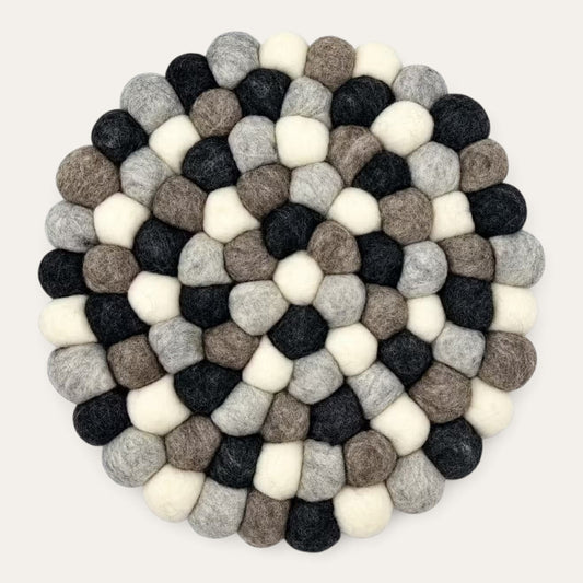 Grey felt ball round placemat seen from above, in charcoal, grey, taupe and cream wool balls