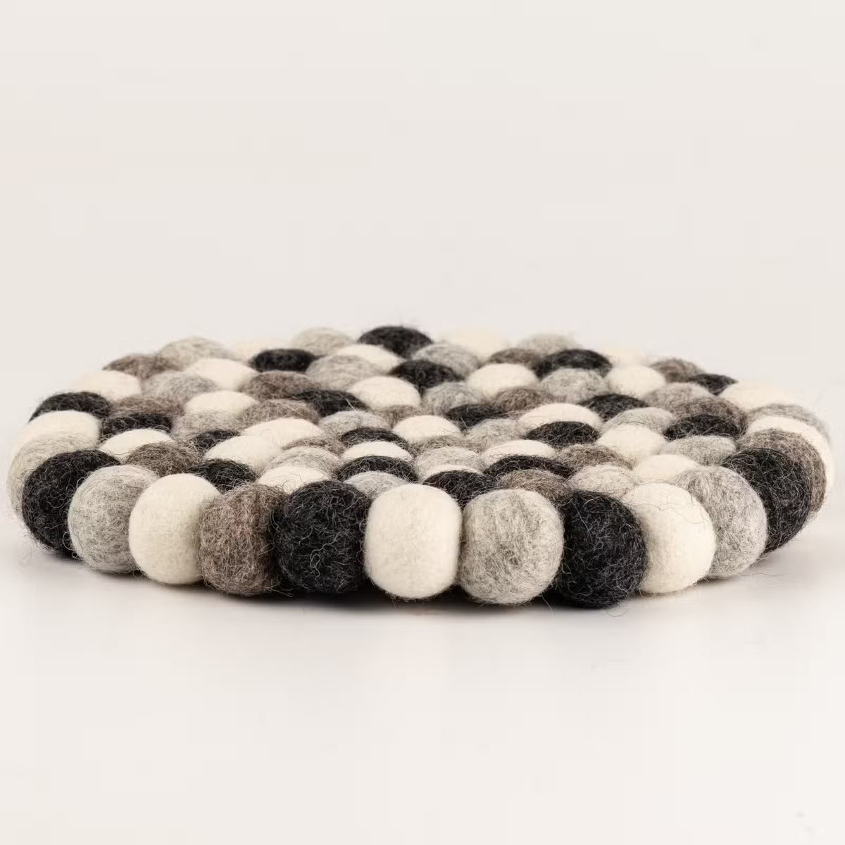 Side view of the grey felt ball round placemat showing its thickness
