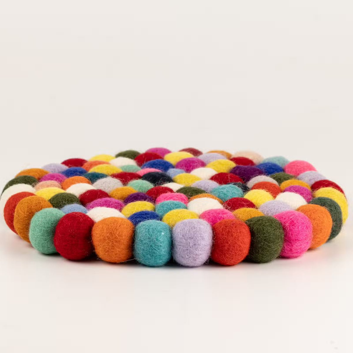Side view of the multicolour felt ball round placemat showing its thickness